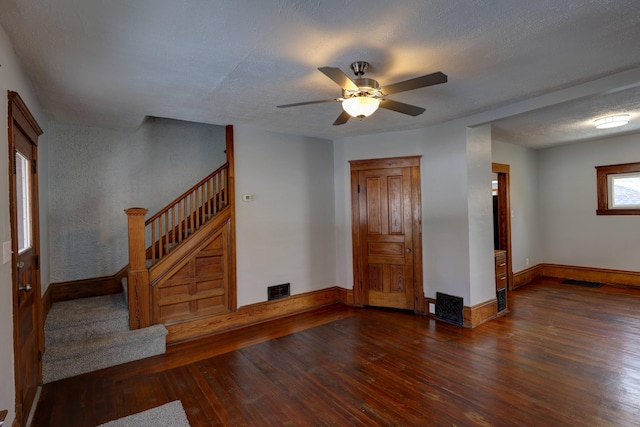 unfurnished living room featuring ceiling fan, dark hardwood / wood-style flooring, and a textured ceiling