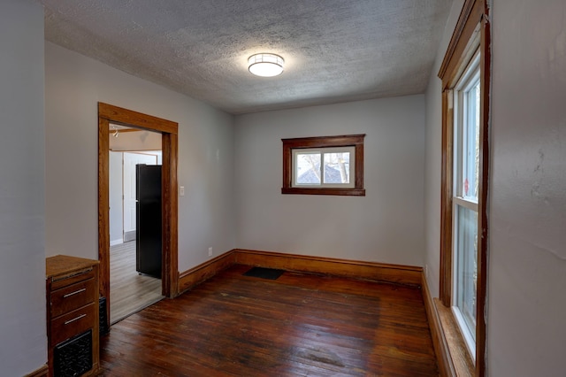 empty room with dark hardwood / wood-style flooring and a textured ceiling