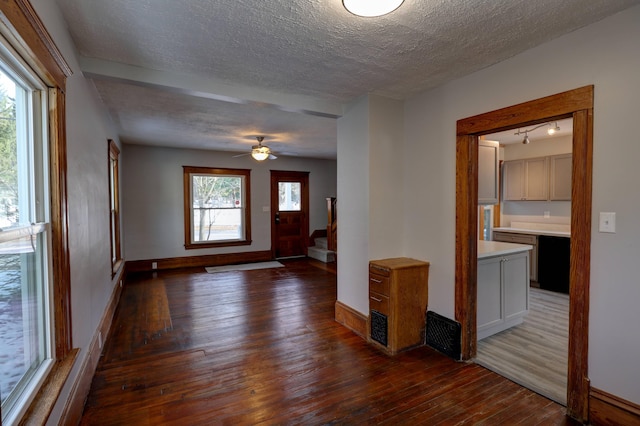 entryway featuring rail lighting, dark wood-type flooring, ceiling fan, and a textured ceiling