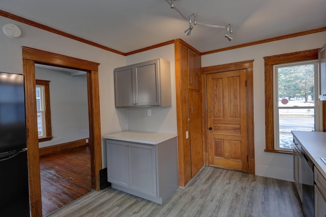 kitchen with gray cabinetry, crown molding, black refrigerator, stainless steel dishwasher, and light hardwood / wood-style floors