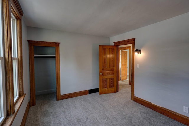 unfurnished bedroom with light colored carpet and a closet