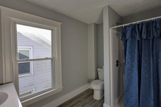 bathroom featuring wood-type flooring, walk in shower, a textured ceiling, and toilet