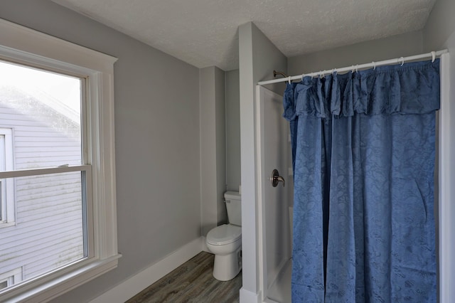 bathroom with a shower with curtain, wood-type flooring, toilet, and a textured ceiling