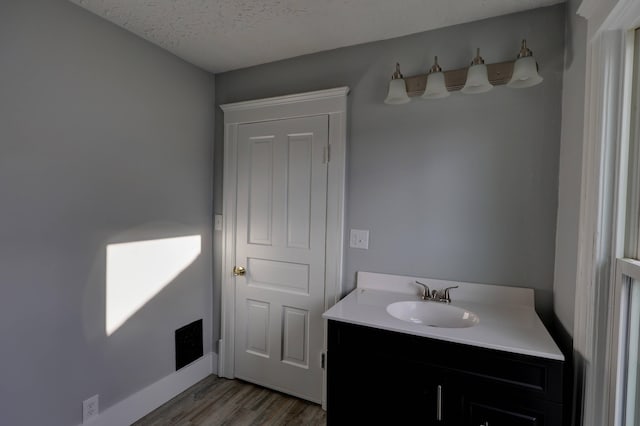 bathroom with vanity, wood-type flooring, and a textured ceiling