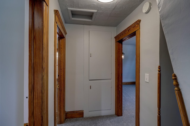 corridor with carpet and a textured ceiling