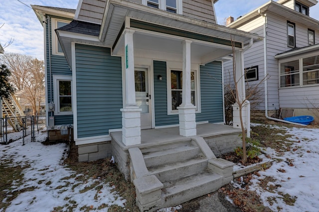 snow covered property entrance featuring a porch