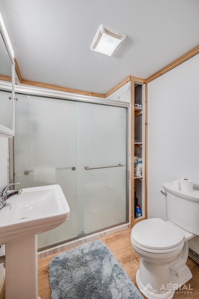 bathroom with hardwood / wood-style flooring, toilet, and a shower with shower door