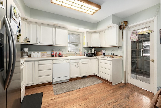 kitchen with white cabinets, white appliances, and light hardwood / wood-style floors