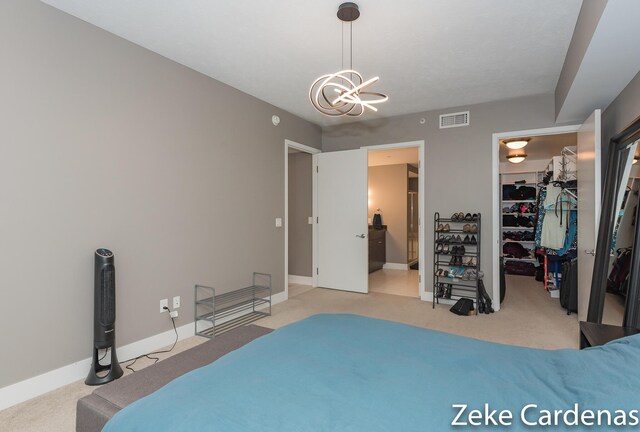 bedroom with an inviting chandelier, a walk in closet, light colored carpet, and a closet