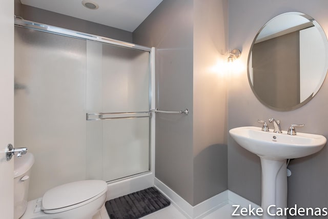 bathroom featuring toilet and a shower with shower door