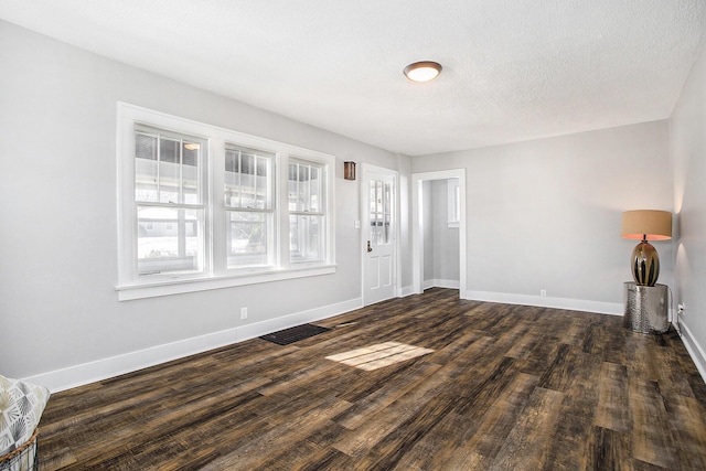 unfurnished living room featuring dark wood-type flooring and a textured ceiling