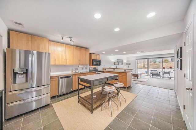 kitchen with a center island, stainless steel appliances, dark tile patterned flooring, and sink