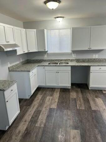 kitchen featuring dark wood-style flooring, built in study area, a sink, and under cabinet range hood