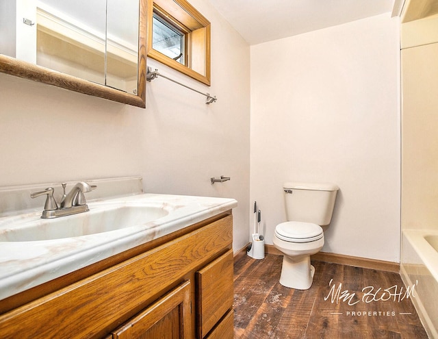 bathroom with hardwood / wood-style floors, vanity, a bath, and toilet