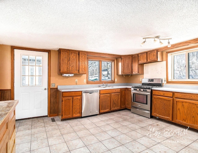 kitchen with sink, light tile patterned floors, a textured ceiling, and appliances with stainless steel finishes