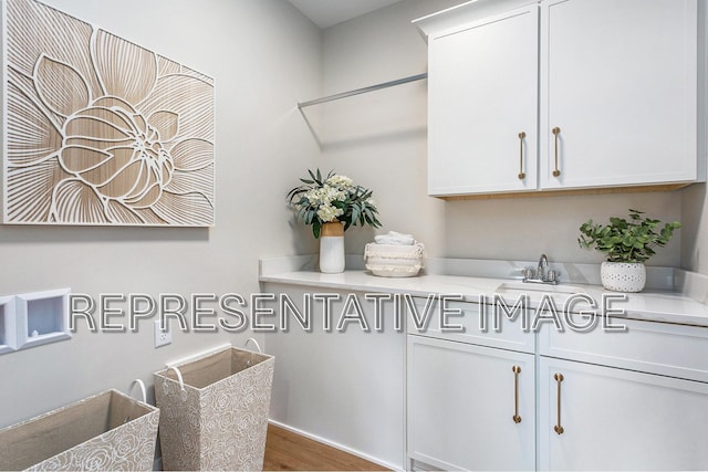 clothes washing area featuring cabinets, sink, and hardwood / wood-style floors