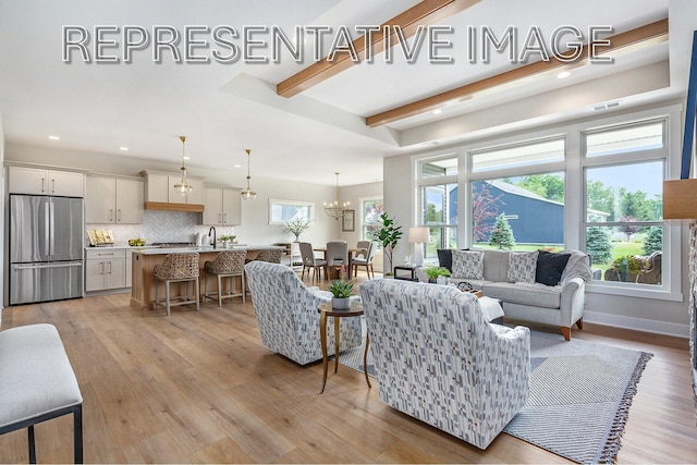 living room with beam ceiling, plenty of natural light, a notable chandelier, and light hardwood / wood-style floors