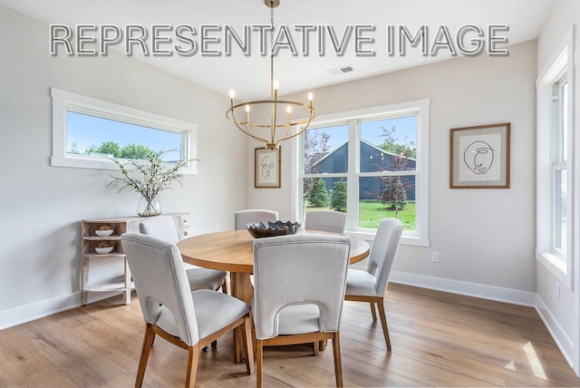 dining area with light hardwood / wood-style floors and a chandelier