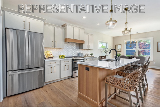 kitchen with white cabinetry, hanging light fixtures, stainless steel appliances, and an island with sink