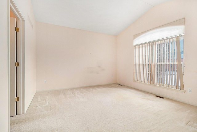 empty room with vaulted ceiling and light colored carpet