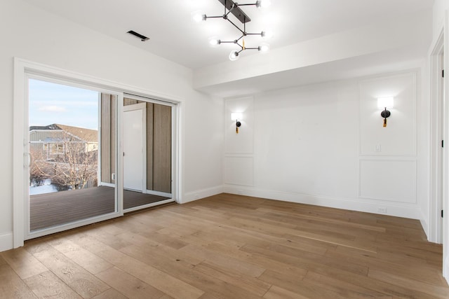 spare room featuring an inviting chandelier and wood-type flooring