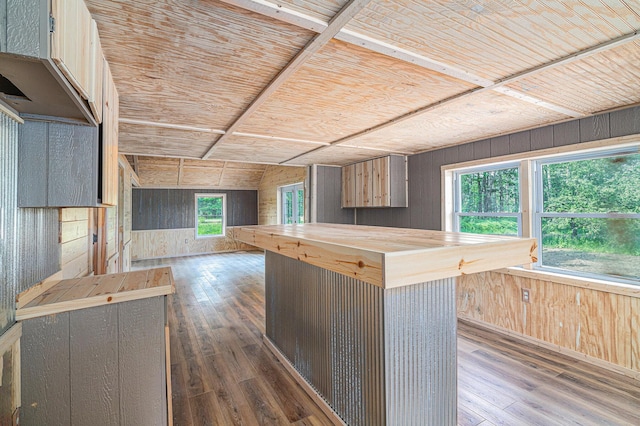 kitchen with a center island, wooden walls, dark hardwood / wood-style flooring, and butcher block countertops