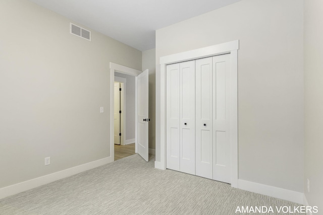 unfurnished bedroom featuring light colored carpet and a closet