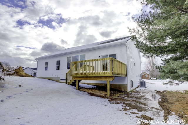 snow covered rear of property featuring central AC and a deck