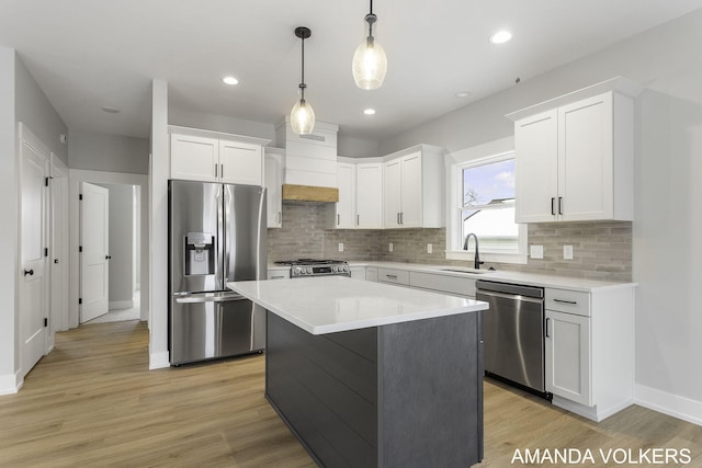 kitchen with sink, hanging light fixtures, appliances with stainless steel finishes, a kitchen island, and white cabinets