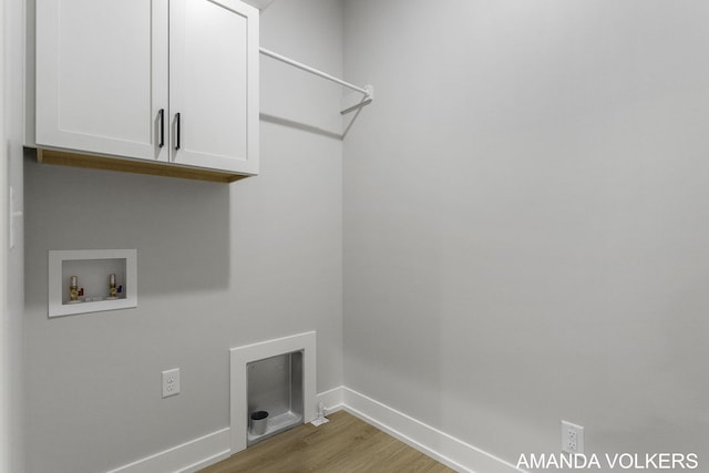 washroom with washer hookup, light hardwood / wood-style floors, and cabinets