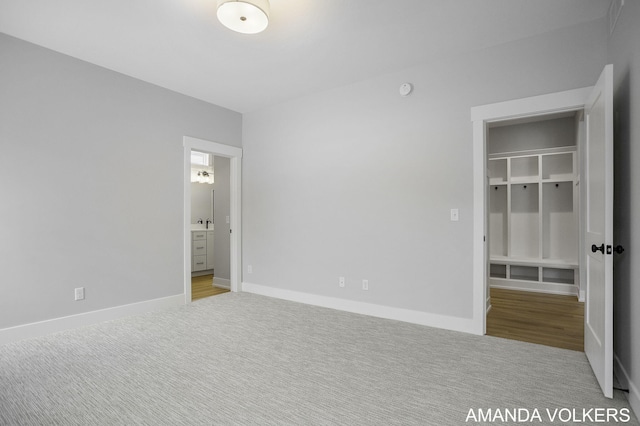 unfurnished bedroom with light colored carpet, connected bathroom, a spacious closet, and a closet