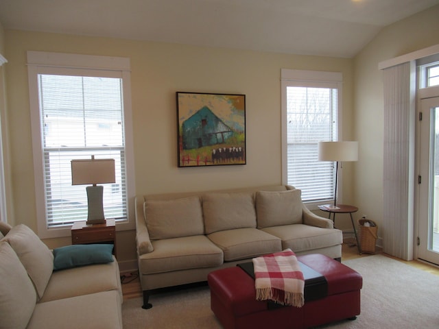 living area featuring a healthy amount of sunlight, carpet, and vaulted ceiling