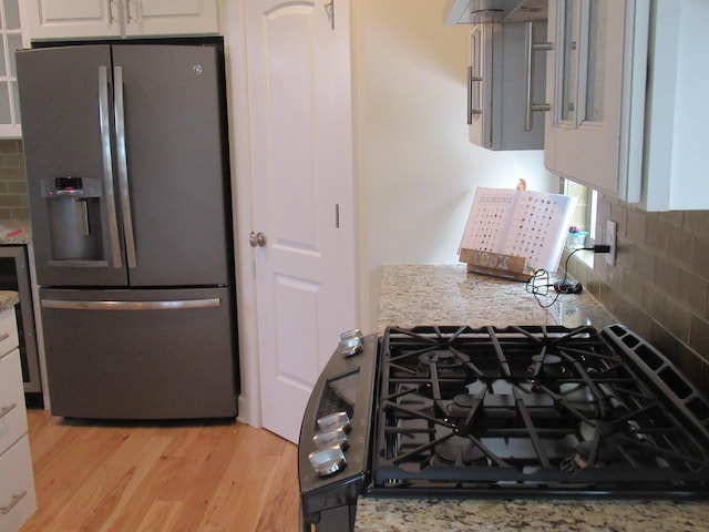 kitchen with white cabinetry, decorative backsplash, light hardwood / wood-style floors, and stainless steel fridge with ice dispenser