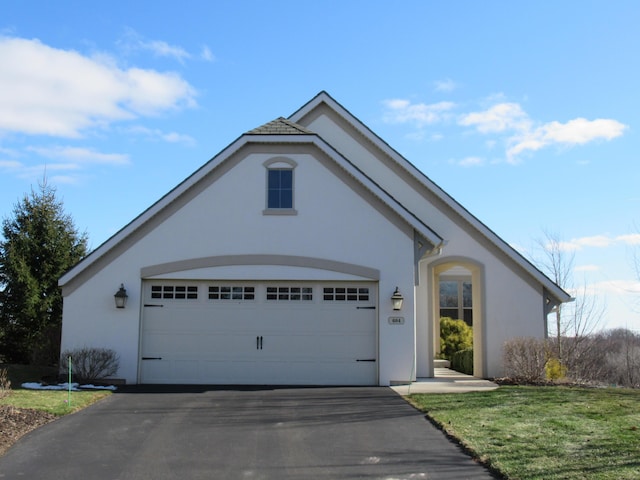 view of front of home featuring aphalt driveway, an attached garage, and stucco siding