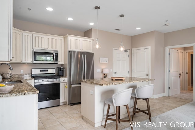 kitchen with pendant lighting, sink, stainless steel appliances, and a kitchen island