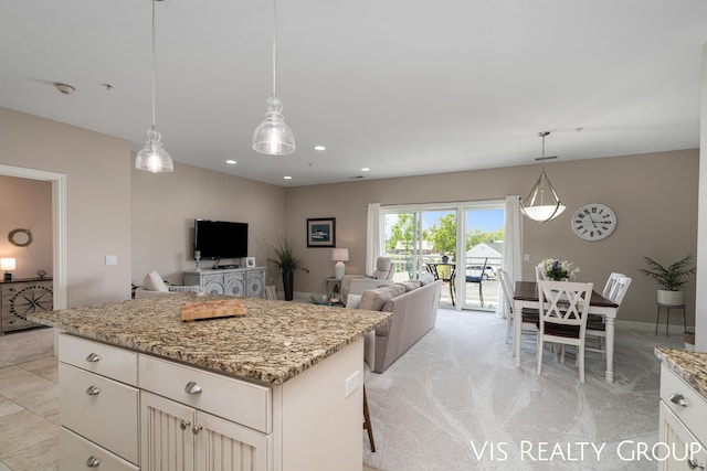 kitchen featuring light stone counters, a center island, hanging light fixtures, a kitchen breakfast bar, and light colored carpet