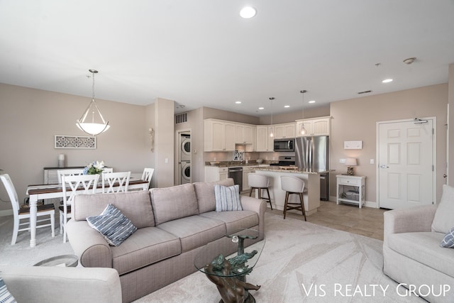 living room with stacked washer / drying machine and light tile patterned floors