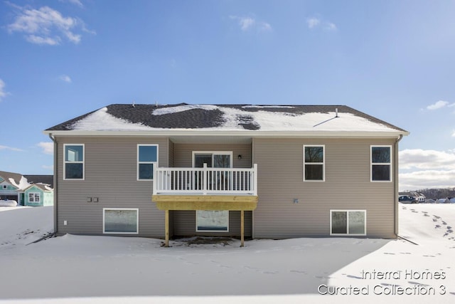 snow covered back of property featuring a balcony