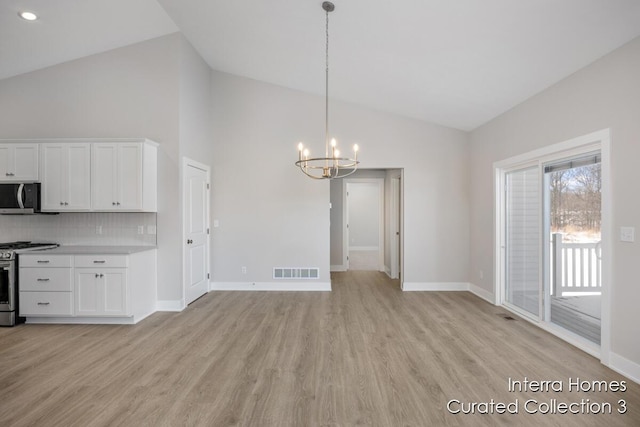 unfurnished dining area with a chandelier, high vaulted ceiling, visible vents, baseboards, and light wood finished floors