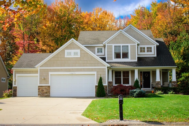 craftsman-style home featuring a garage, covered porch, and a front lawn