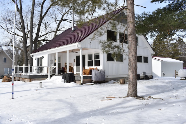 snow covered rear of property featuring covered porch