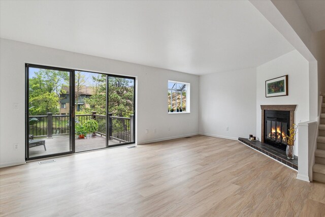 unfurnished living room with light wood-style floors, a glass covered fireplace, and baseboards