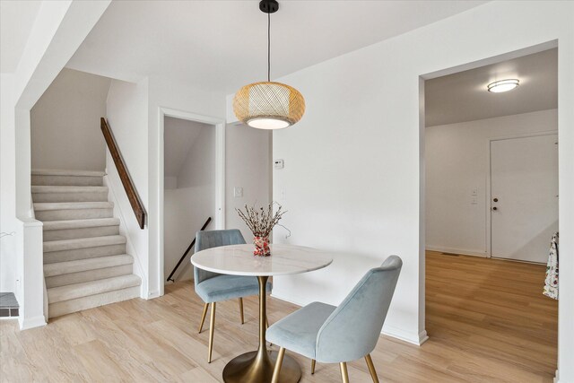 dining area with light wood-style flooring, stairway, and baseboards