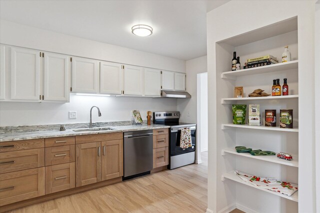 kitchen with appliances with stainless steel finishes, a sink, open shelves, under cabinet range hood, and light stone counters