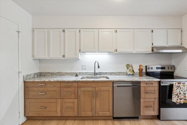 kitchen with stainless steel appliances, a sink, white cabinets, under cabinet range hood, and light wood finished floors