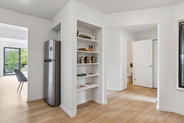 hall featuring light wood finished floors and baseboards