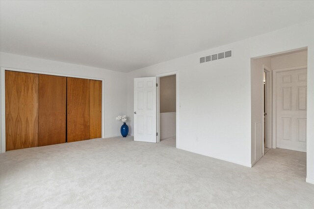 unfurnished bedroom with light colored carpet, a closet, and baseboards
