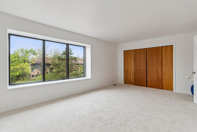 unfurnished bedroom with a closet, carpet, and baseboards