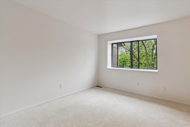 unfurnished room with light colored carpet and baseboards