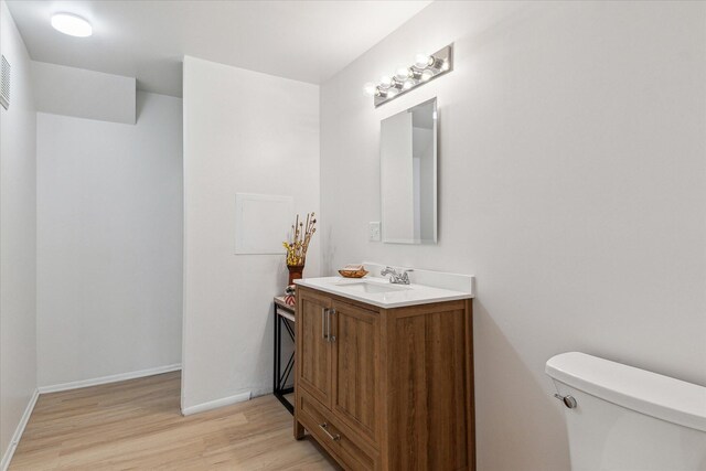 bathroom featuring wood finished floors, toilet, vanity, and baseboards